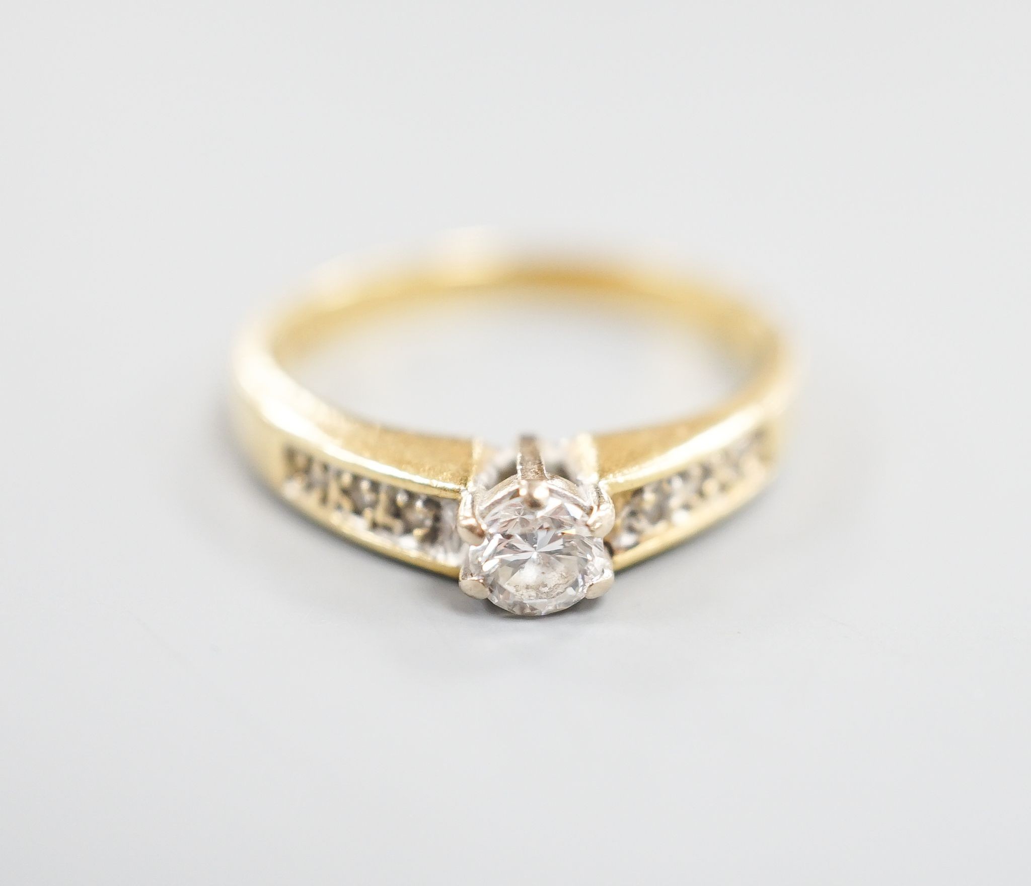 A modern 18ct gold and single stone diamond ring, with diamond set shoulders, size L, gross 2.4 grams.